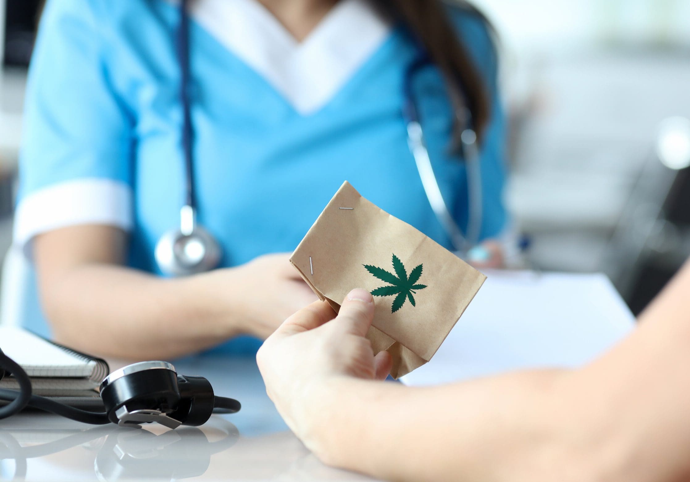 Female doctor writes prescription for medical marijuana to patient in hospital office. Legal marijuanna treatment concept