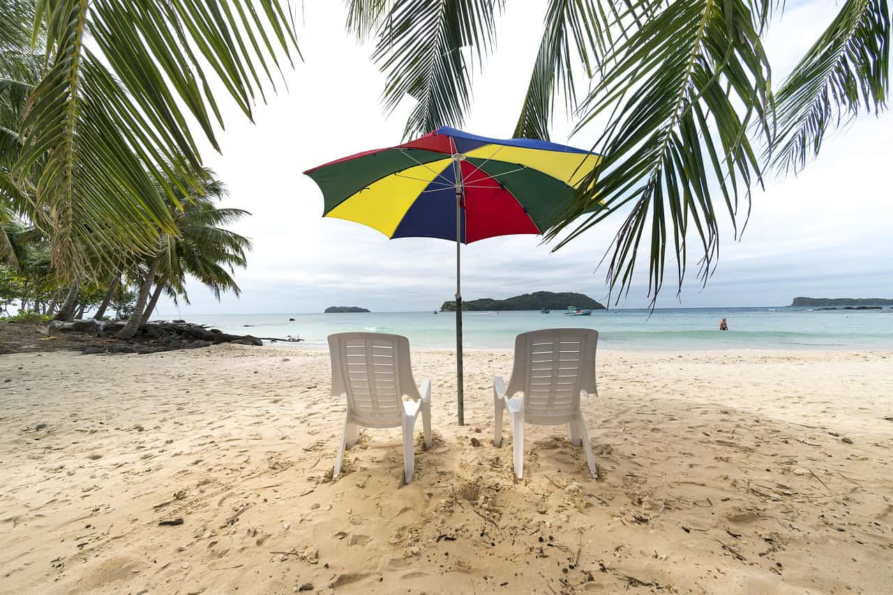 Two beach chairs under an umbrella on a Florida beach